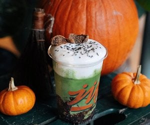 green matcha drink with foam on table with pumpkins